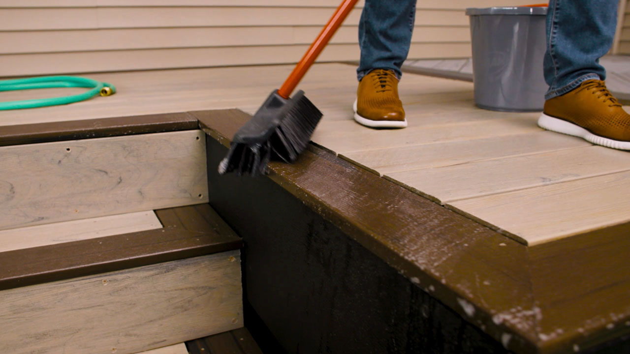 Soft-bristle brush cleaning Armadillo composite deck boards for deck maintenance tips