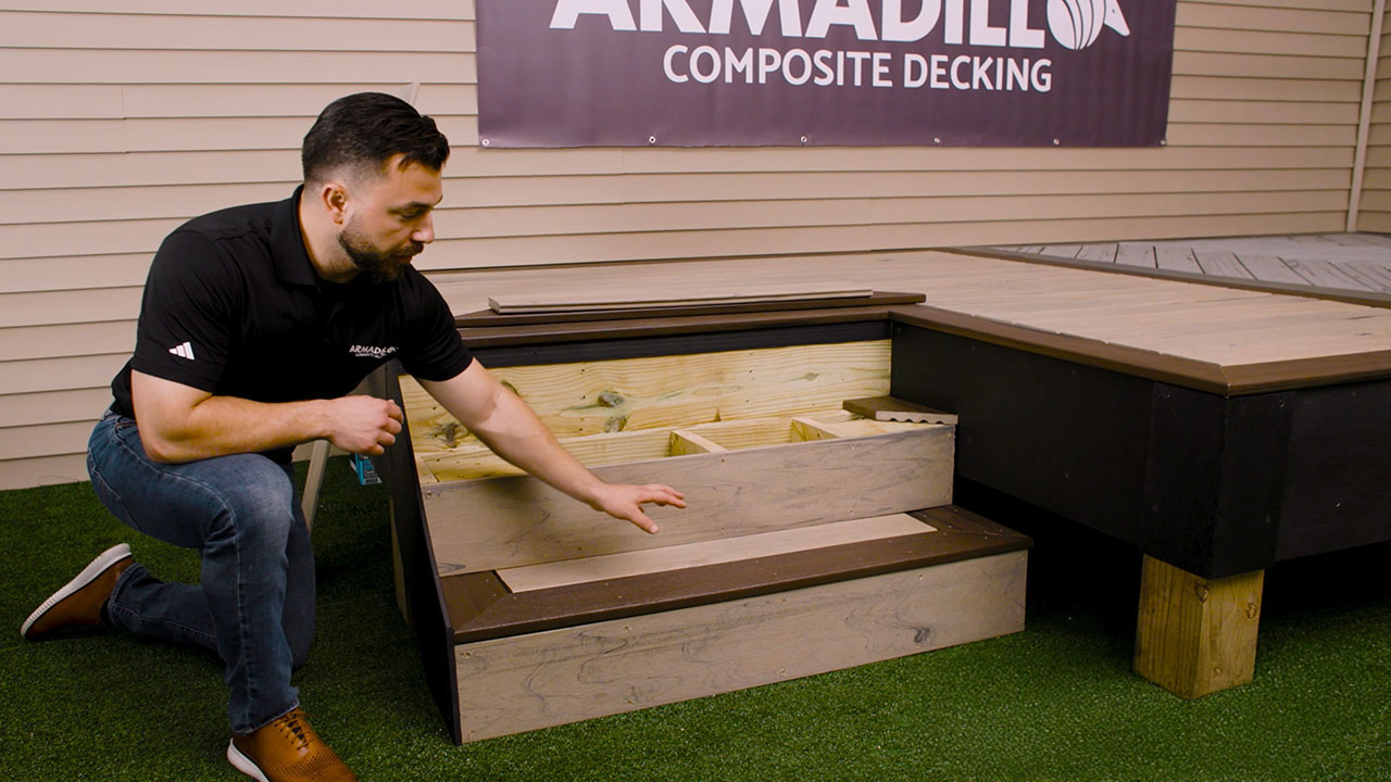 Derek kneeling by steps pointing to composite deck treads and risers with contrasting boards