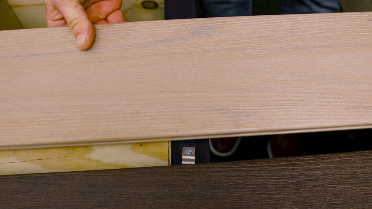 Stainless steel C-clip installed on composite deck transition board with the TurboClip hidden fastener system