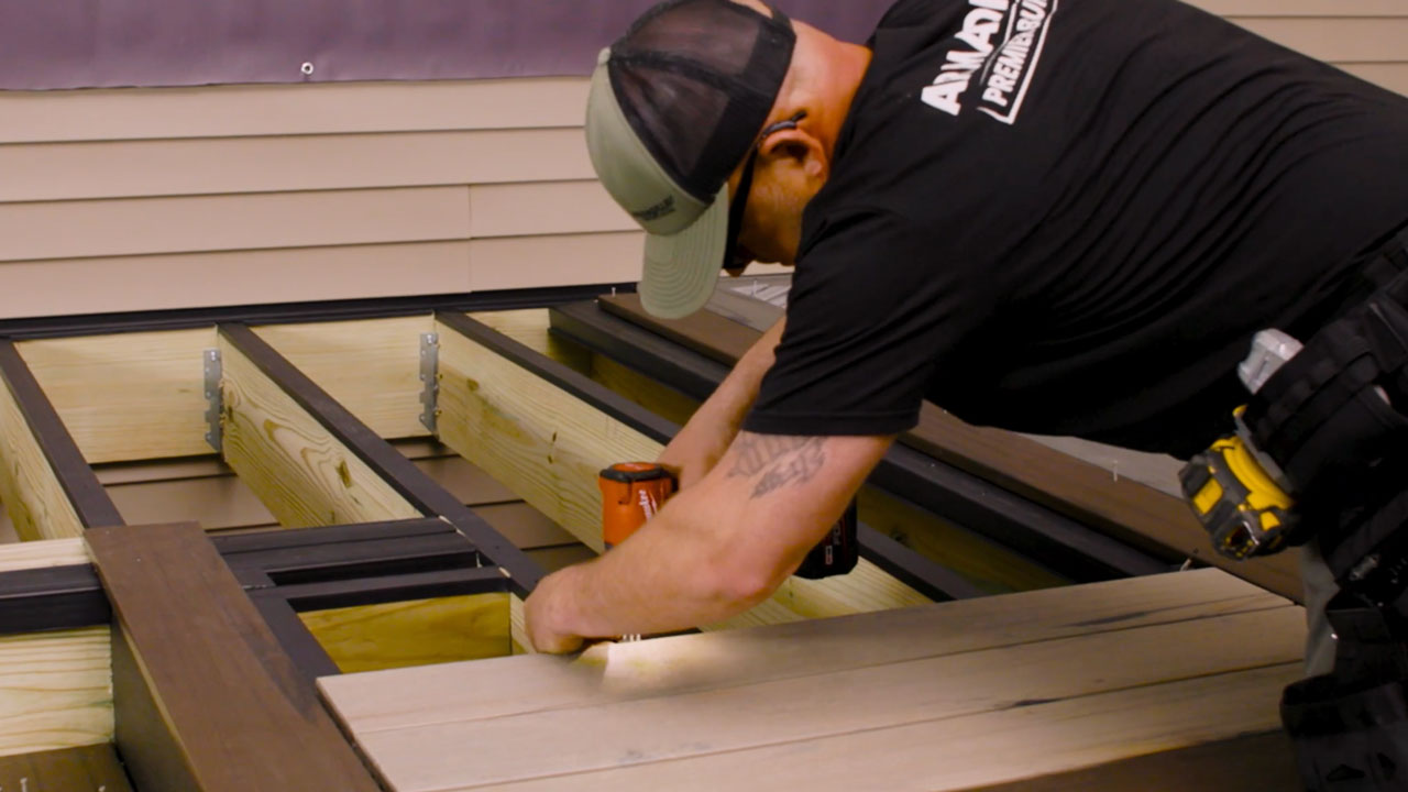 Installer securing composite deck boards with TurboClip hidden fastener system using T15 screw